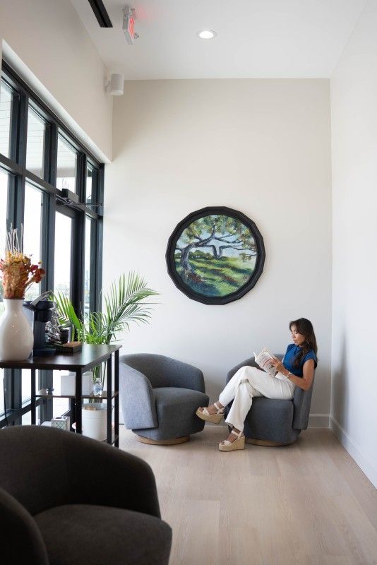 Woman sitting in a bright lounge chair and using a laptop in a modern waiting area - Transcend Dental Office Photo