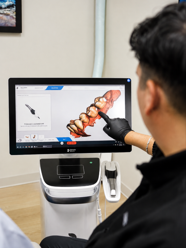 A woman is smiling while sitting in a dental chair.