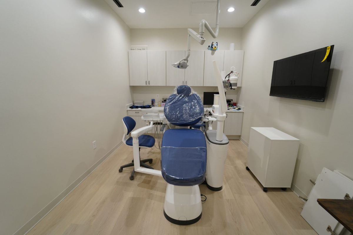 Dental treatment room with a blue dental chair, overhead lights, and wall-mounted monitor - Transcend Dental Office Photo