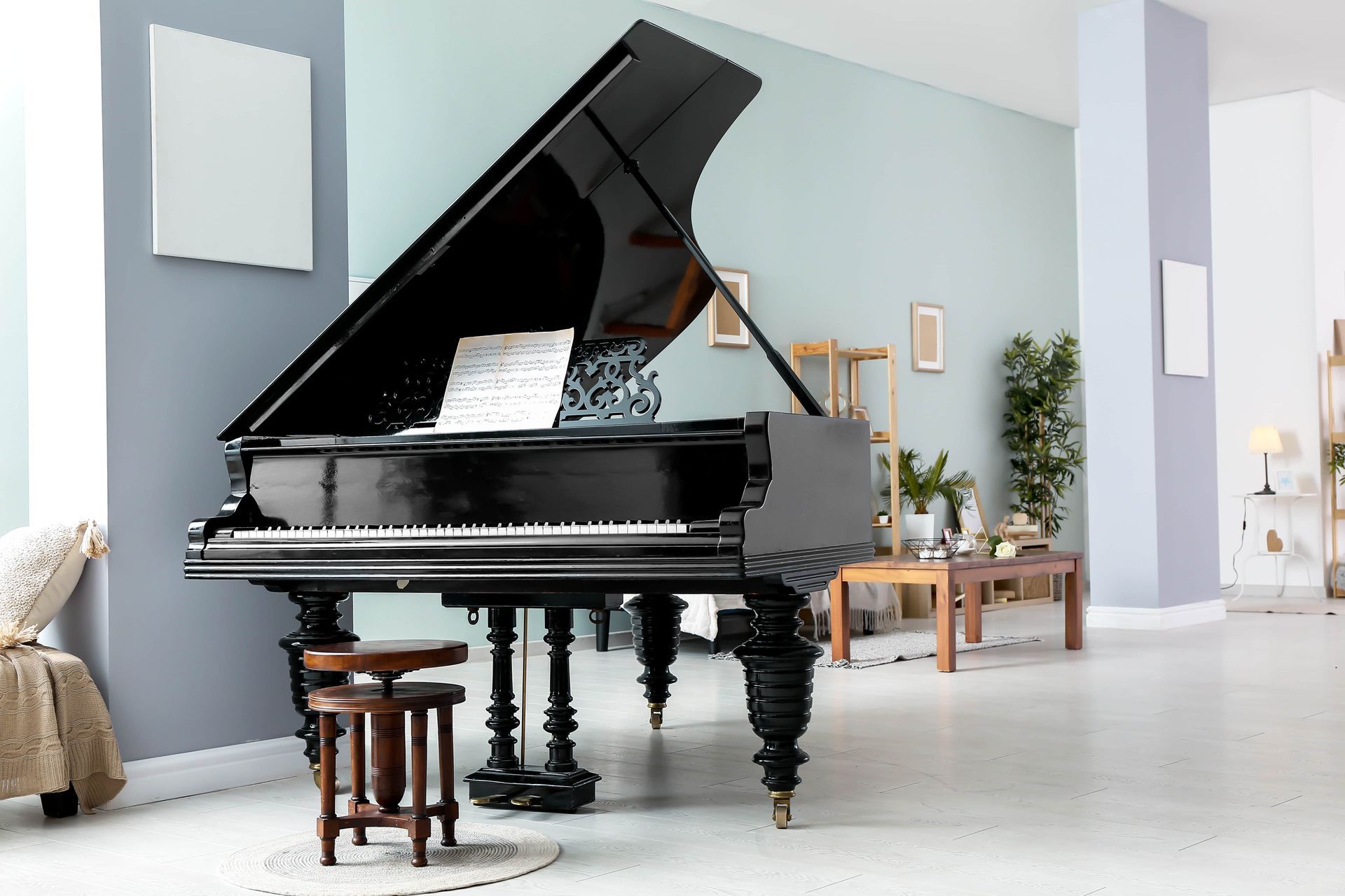 Black grand piano in a bright modern room with a bench and small table nearby