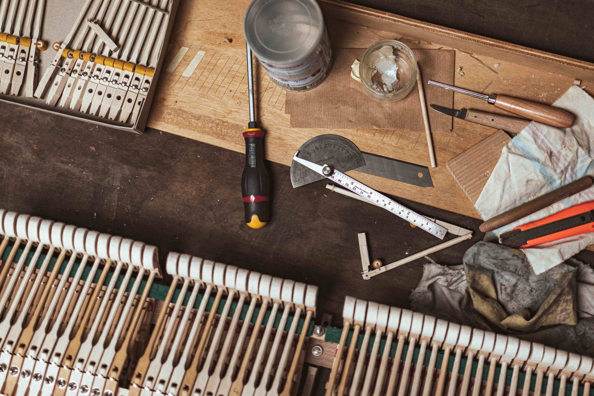 Piano action parts and repair tools laid out on a workbench