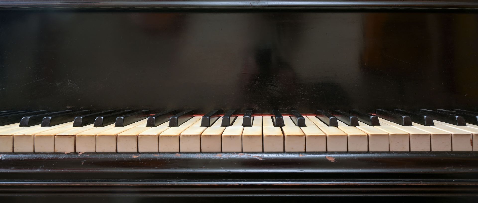 Black upright piano with white and black keys against a dark background