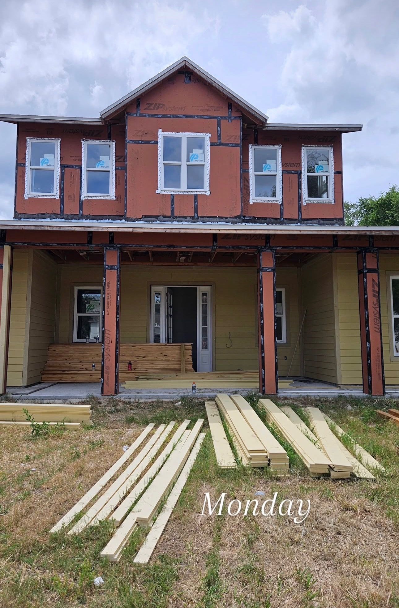Partly restored red and cream house with porch and lumber laid in front yard - BittnerSweet Co.