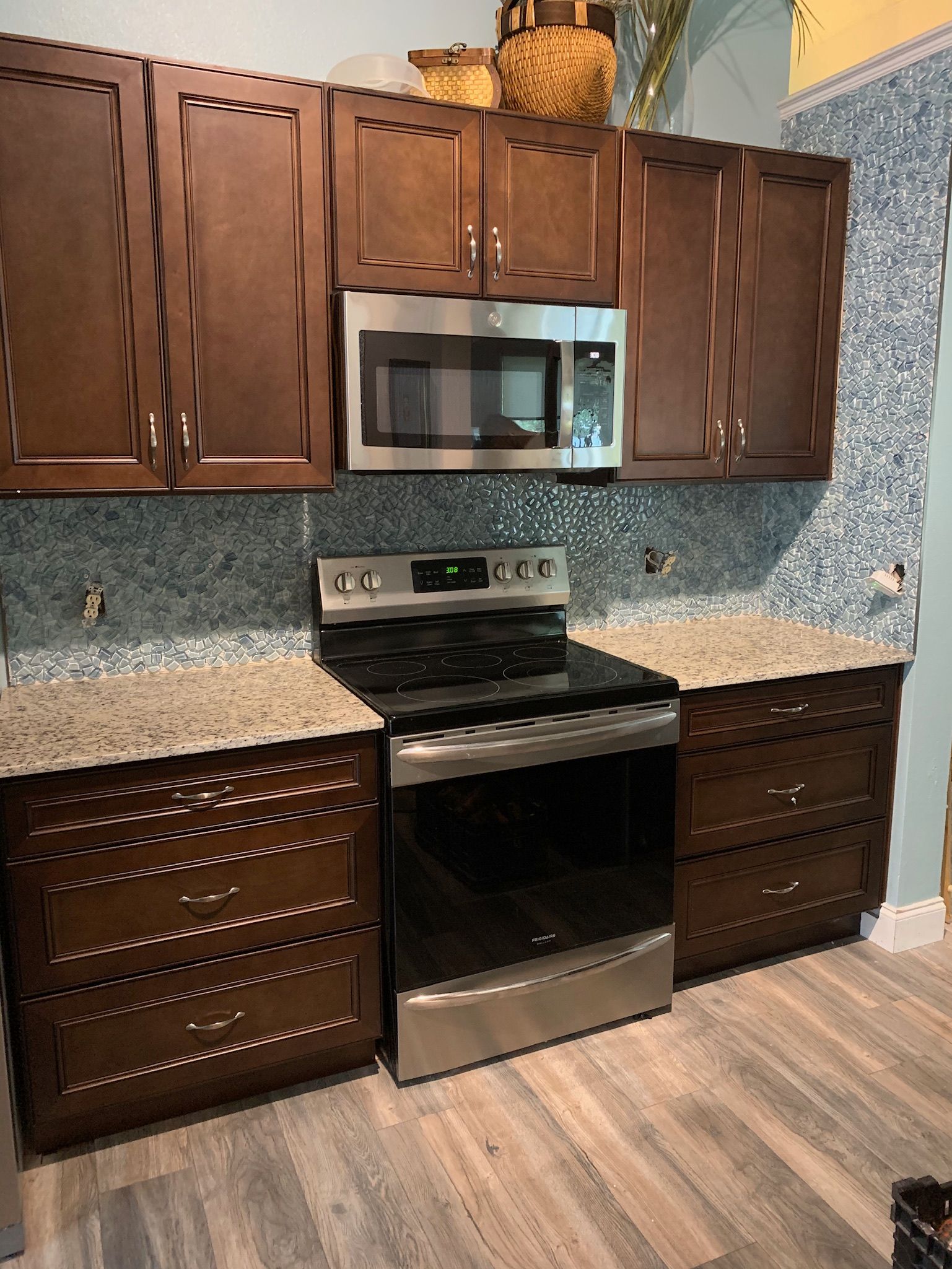 Dark wood kitchen cabinets with stainless steel oven and microwave, stone backsplash, and granite countertops. - BittnerSweet Co.