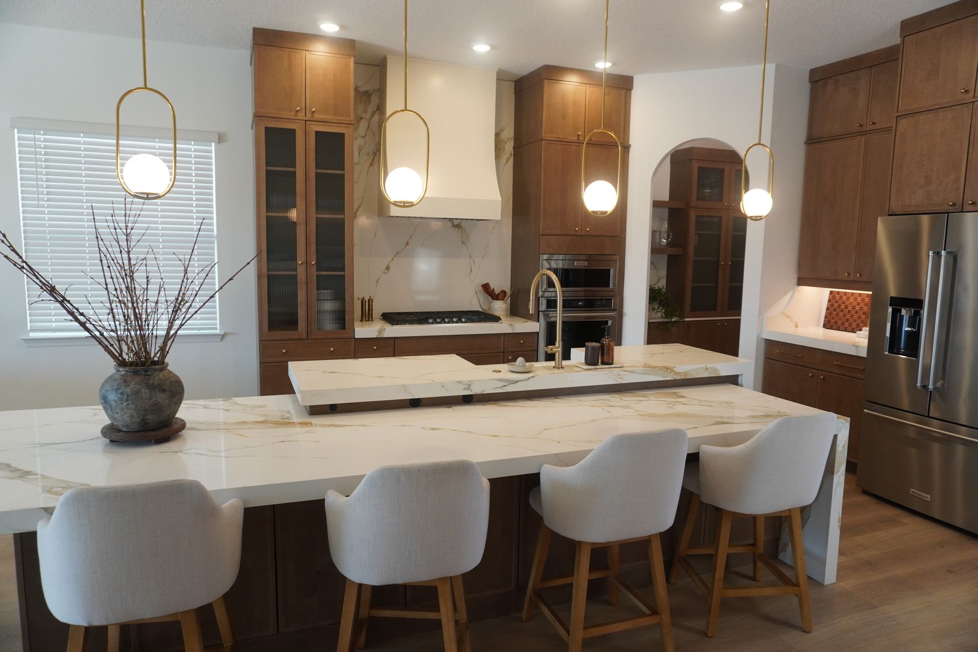 Modern kitchen with a large island, pendant lights, wood cabinets, and stainless steel appliances - BittnerSweet Co.
