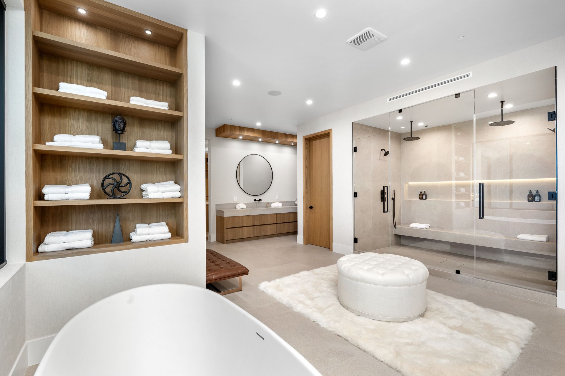 Bright modern bathroom with wood shelves, round tub, vanity, and glass walk-in shower - BittnerSweet Co.