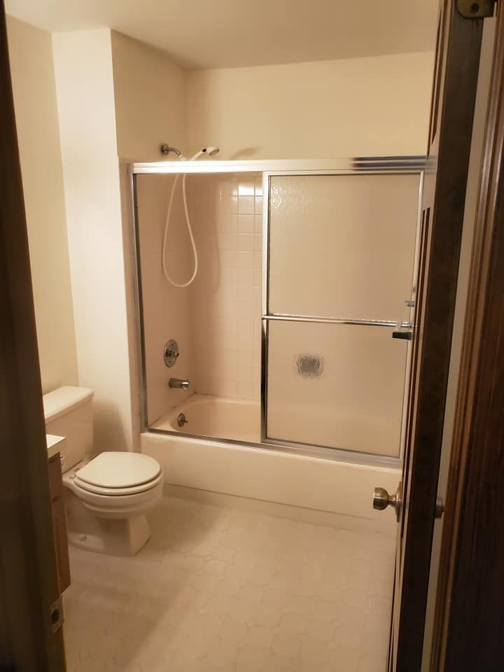 A bathroom view showing a white toilet next to a bathtub and shower combination enclosed by glass sliding doors.