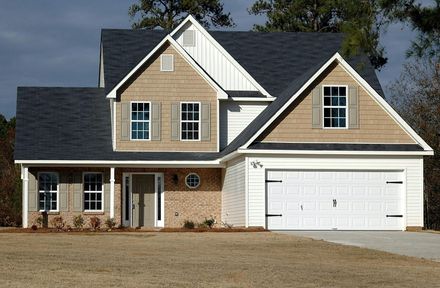 A two-story suburban house with a brick and white exterior, a white two-car garage, and a dark roof.
