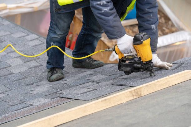 Close-up of a roofer showcasing roofing services installing asphalt with a nail gun.