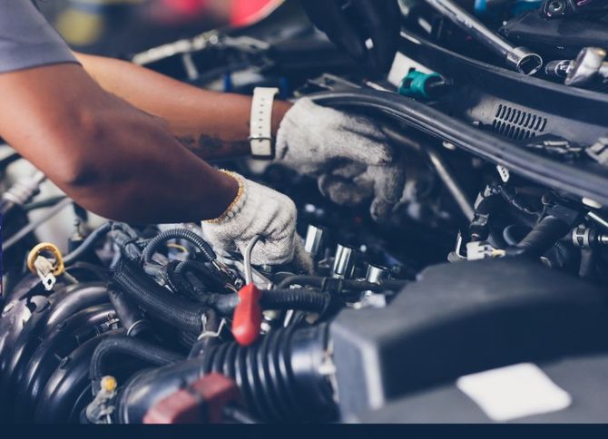 Mechanic wearing gloves working on a car engine in a workshop