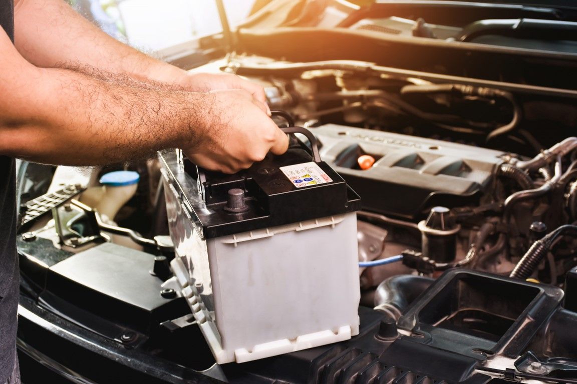 Hands installing a car battery in an open engine bay