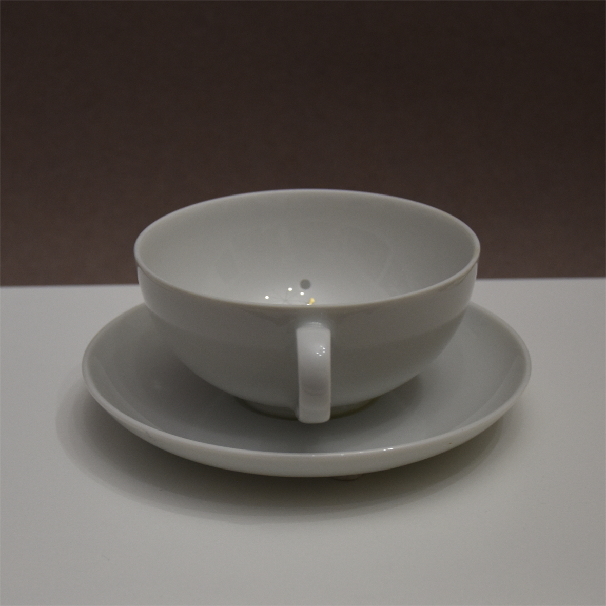 Titel: Gönnen können
Ansicht seitlich.
Die Plastik der Künstlerin Benita von Wendt besteht aus einer durchlöcherten Tasse,  die auf einer Untertasse steht. In der Tasse ist der Schriftzug 