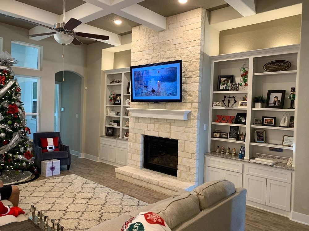 A living room with a fireplace , couch , television and a christmas tree.
