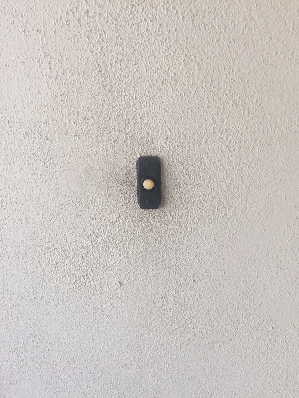 A small black object is hanging on a white wall.