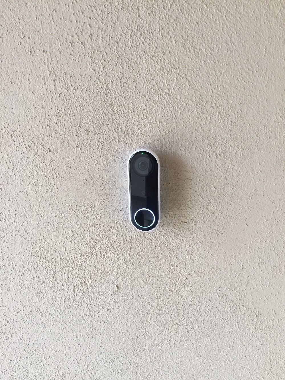 A doorbell is hanging on a white wall.