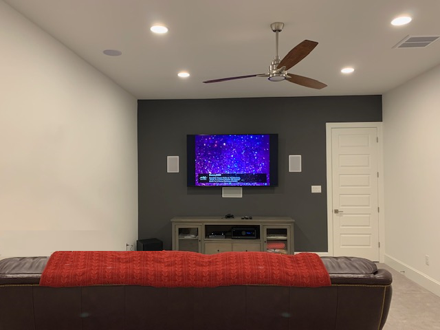 A living room with a ceiling fan and a flat screen tv