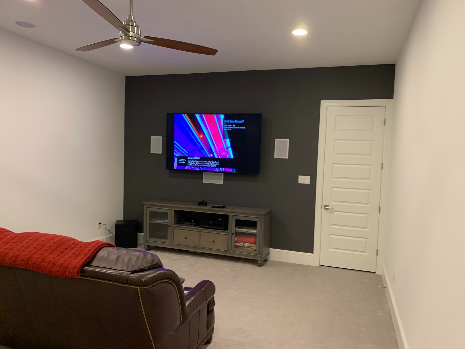 A living room with a couch , television , and ceiling fan.