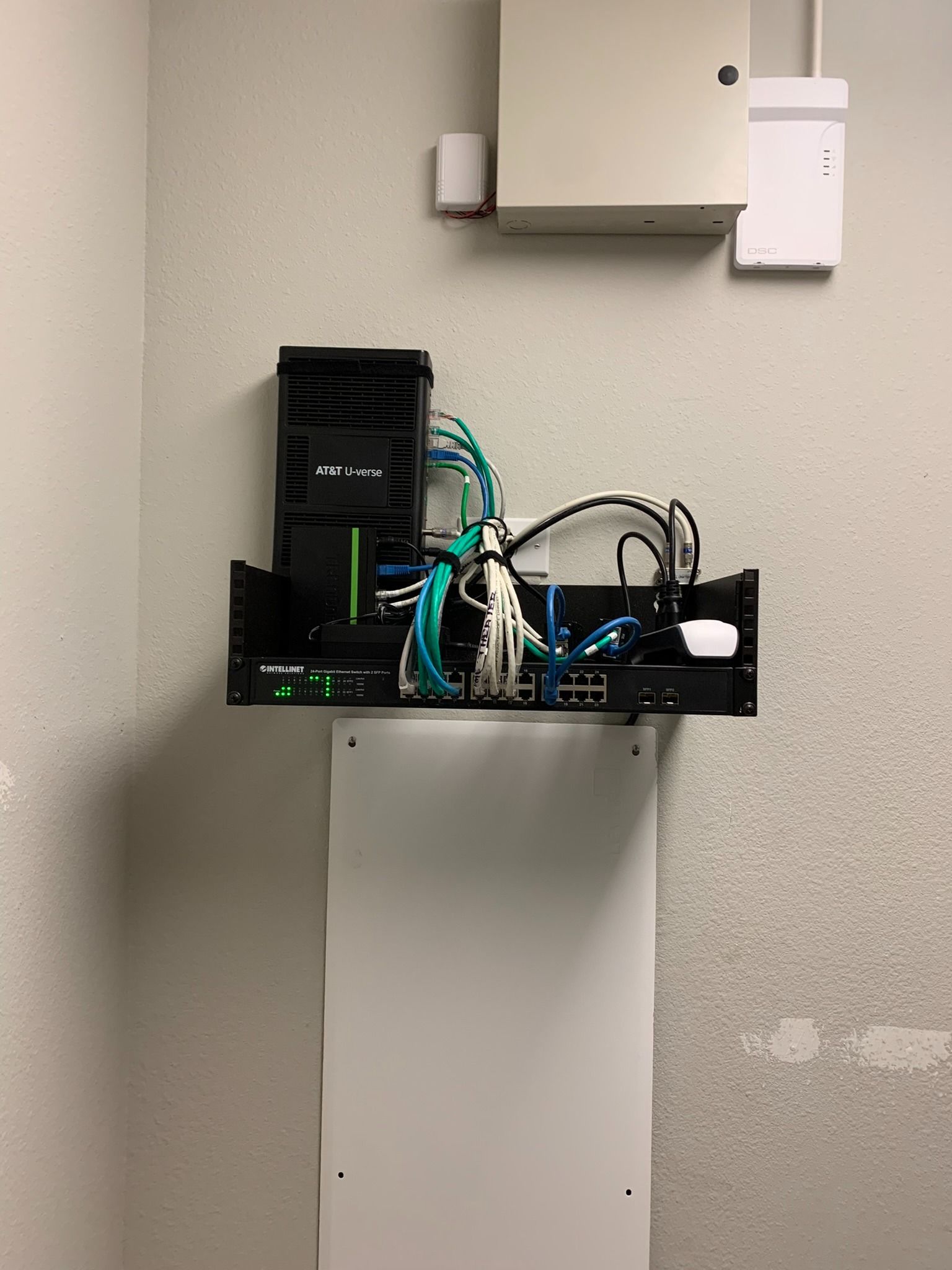 A shelf with a bunch of wires hanging from it on a wall.