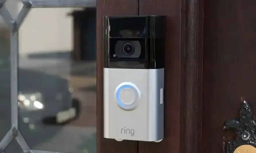A ring doorbell is sitting on a wooden door.