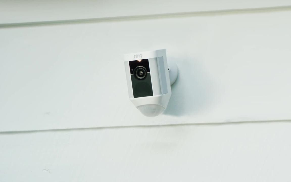 A security camera is mounted on the side of a house.