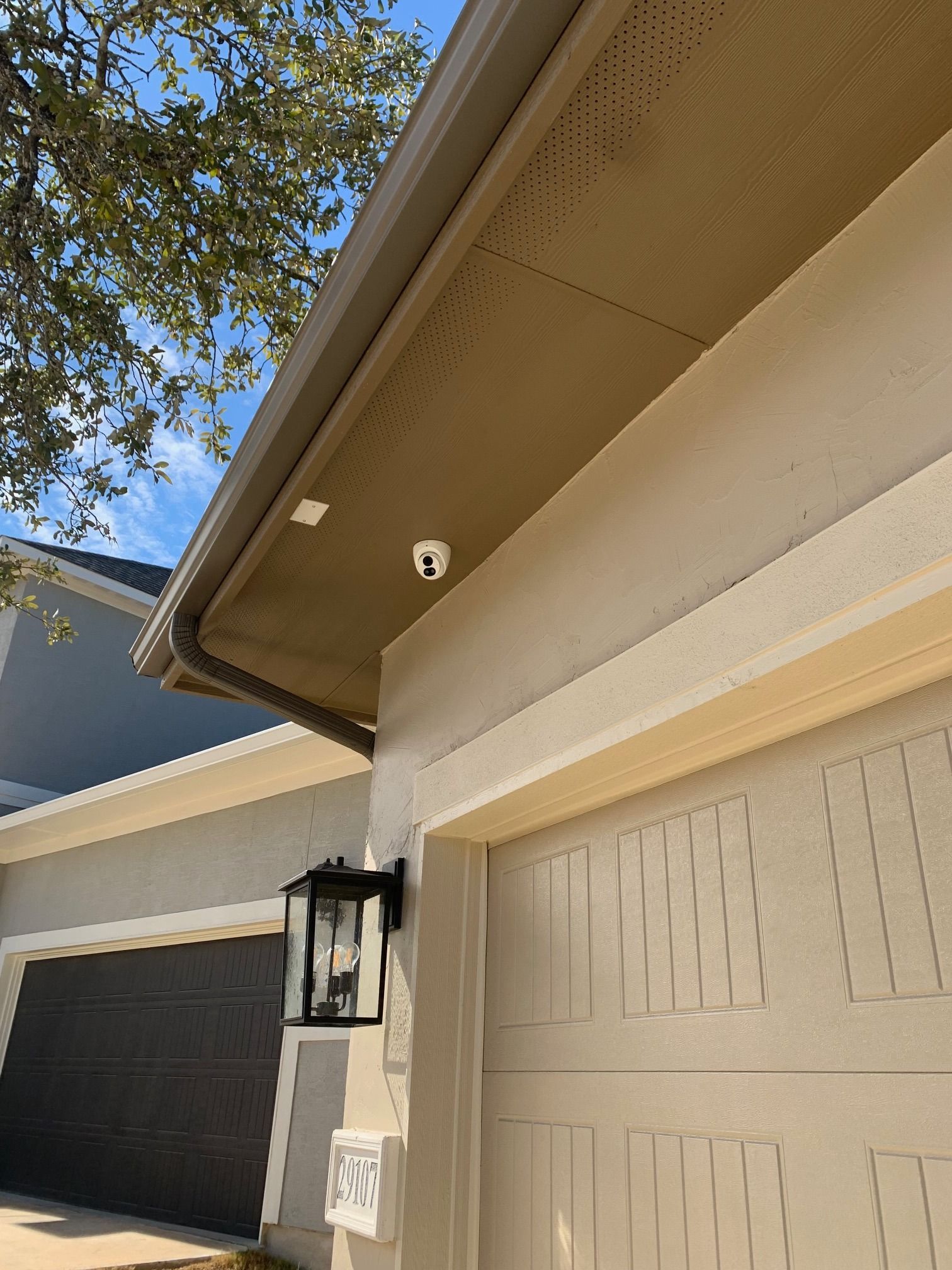 A house with two garage doors and a camera on the roof.