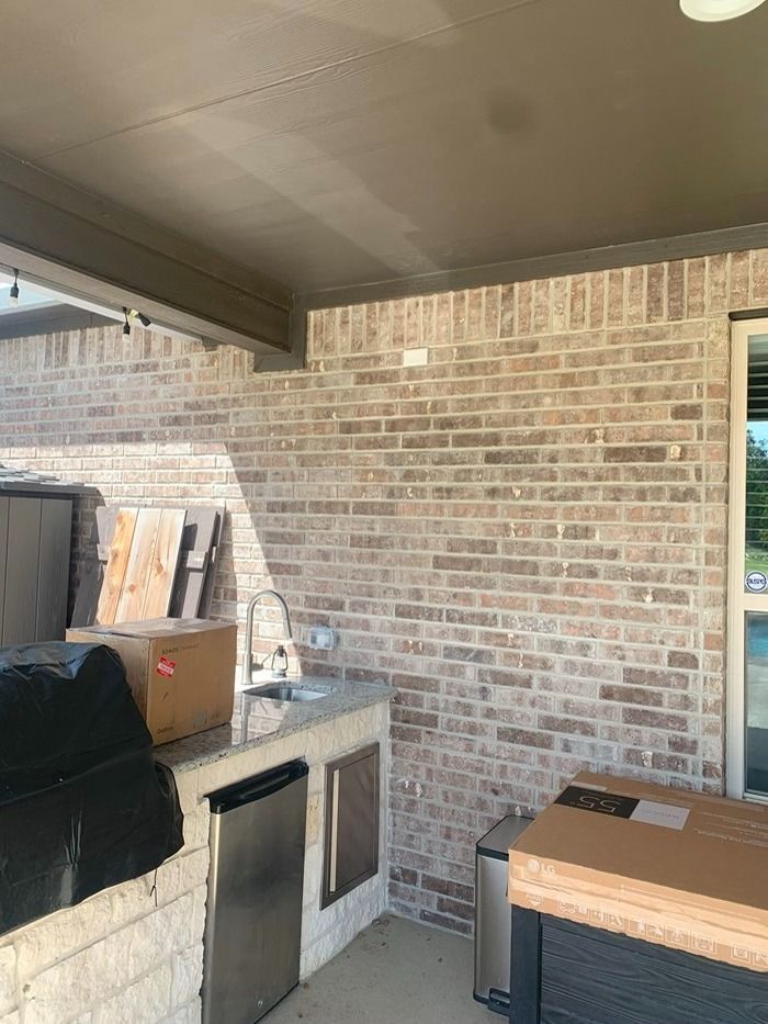 A kitchen with a brick wall , stainless steel appliances , a sink , and a grill.