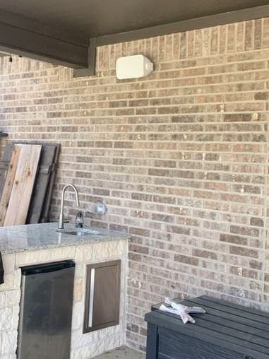 A brick wall with a sink and a bench in front of it.