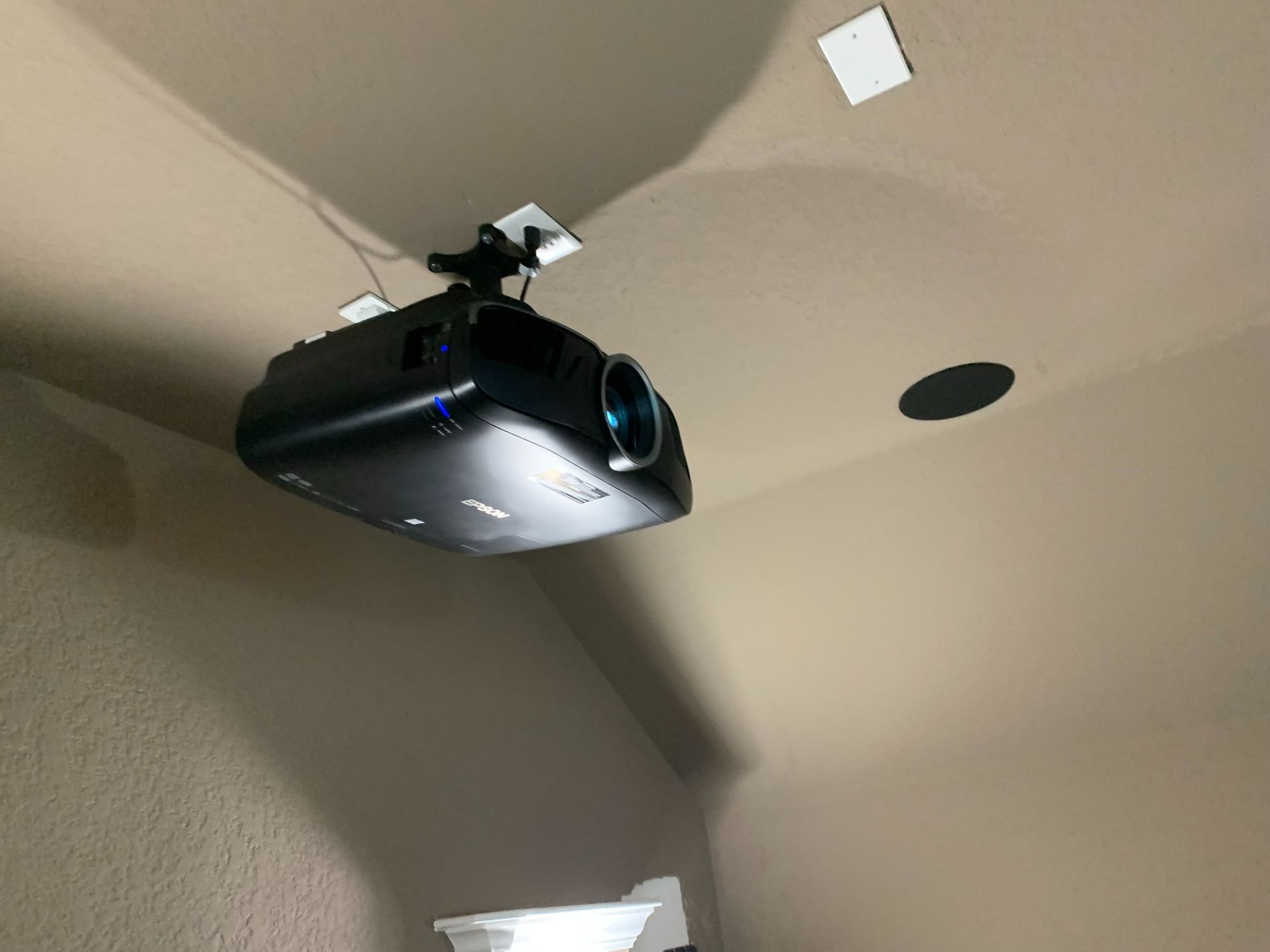 A projector is hanging from the ceiling of a room.