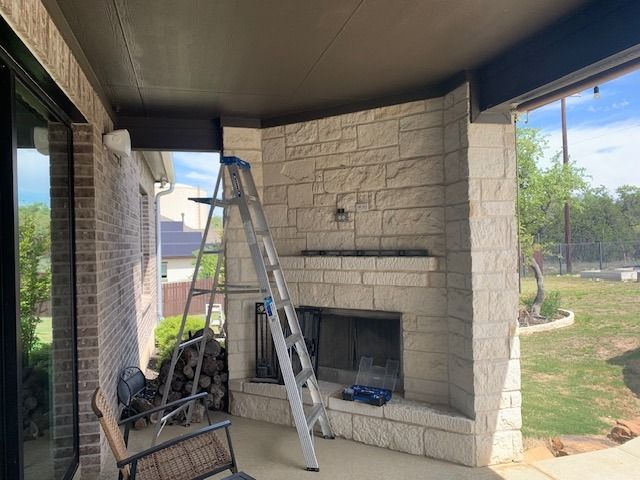 A ladder is sitting on a porch next to a fireplace.