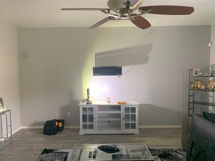 A living room with a ceiling fan and a television on the wall.