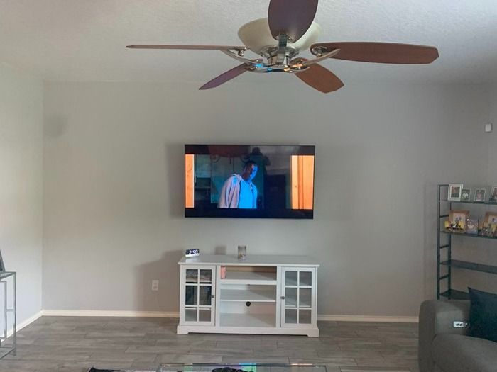 A living room with a flat screen tv and a ceiling fan