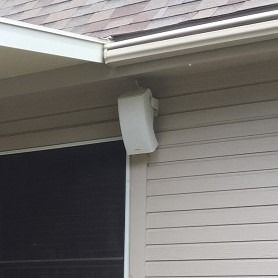 A speaker is mounted on the side of a house.