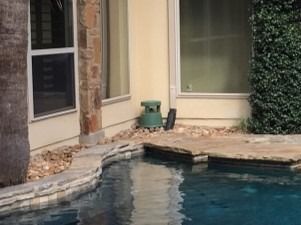 There is a swimming pool in the backyard of a house.