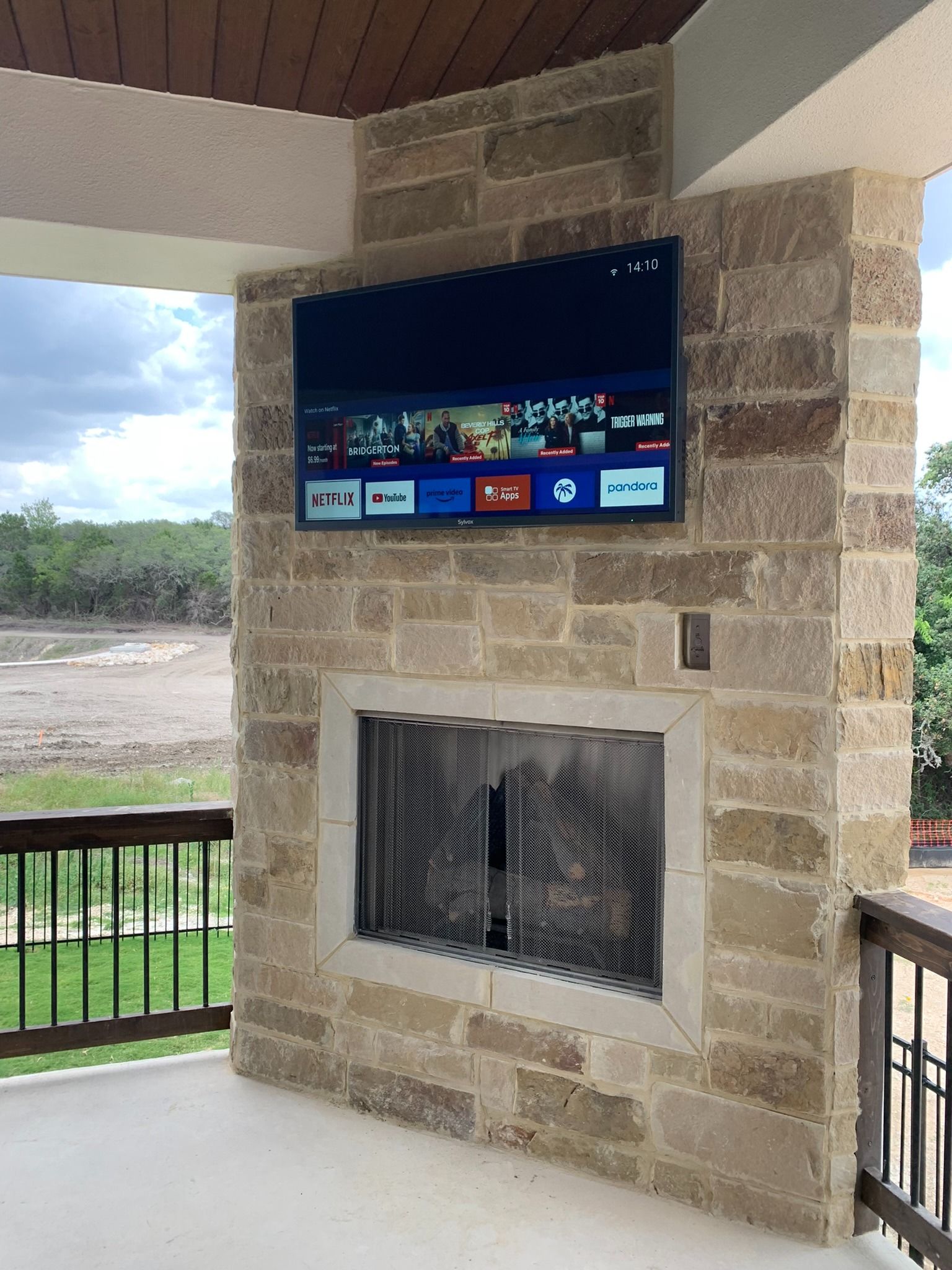 A large flat screen tv is mounted above a fireplace.