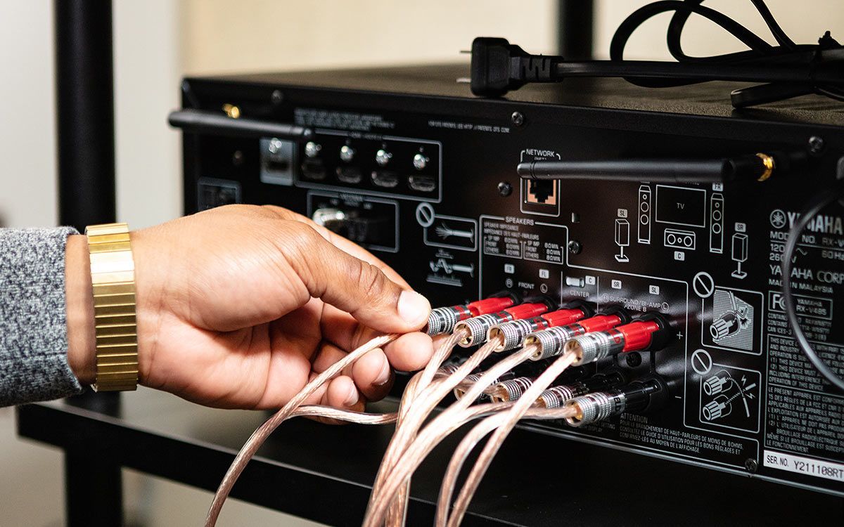 A person is plugging wires into a receiver.