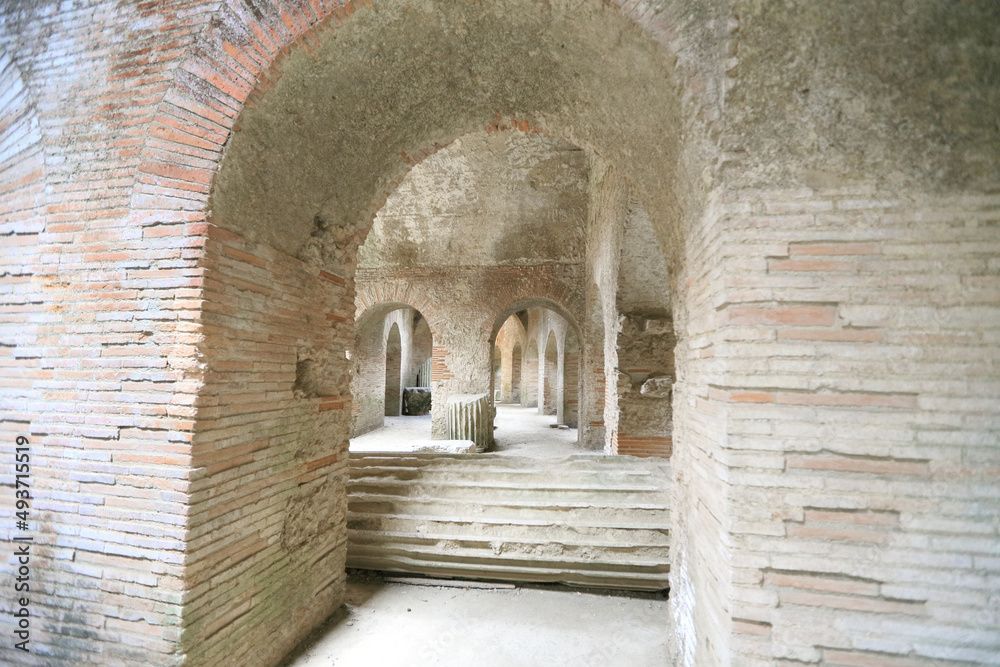 Arched brick hallway with stone steps and repeating archways in a historic interior