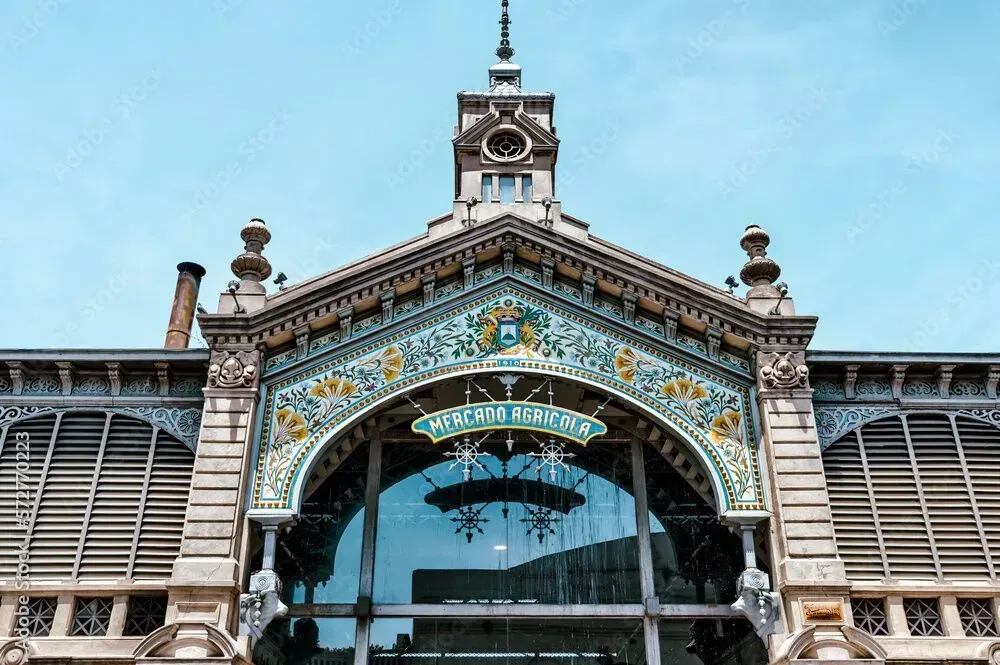 Ornate historic market building facade with a central arch, clock tower, and blue decorative tiles.