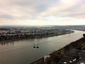 Wide river with a cityscape and hills in the distance, viewed from a high riverbank.