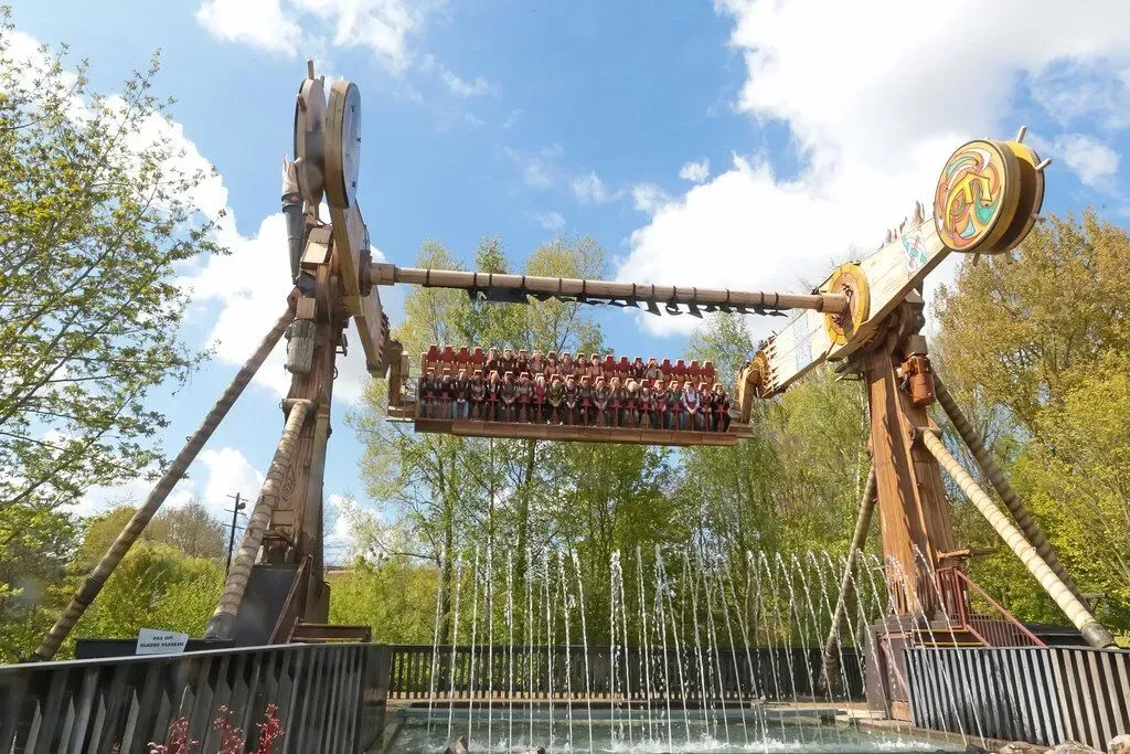 Roller coaster with riders looping through steel tracks under a bright blue sky