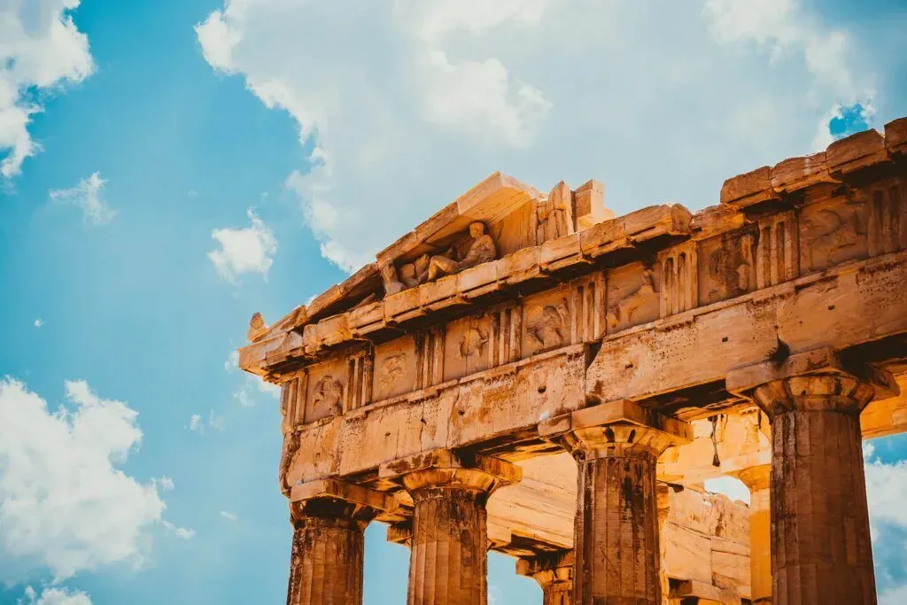 Ancient stone temple ruins against a bright blue sky with clouds