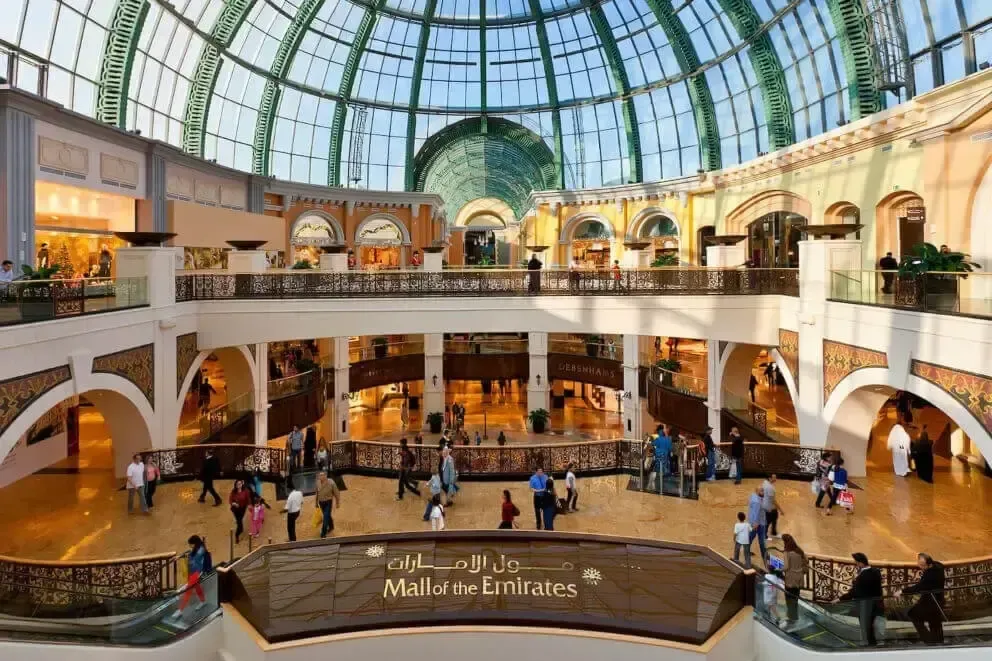 Grand atrium of The Mall of the Emirates with glass dome, arches, and shoppers below