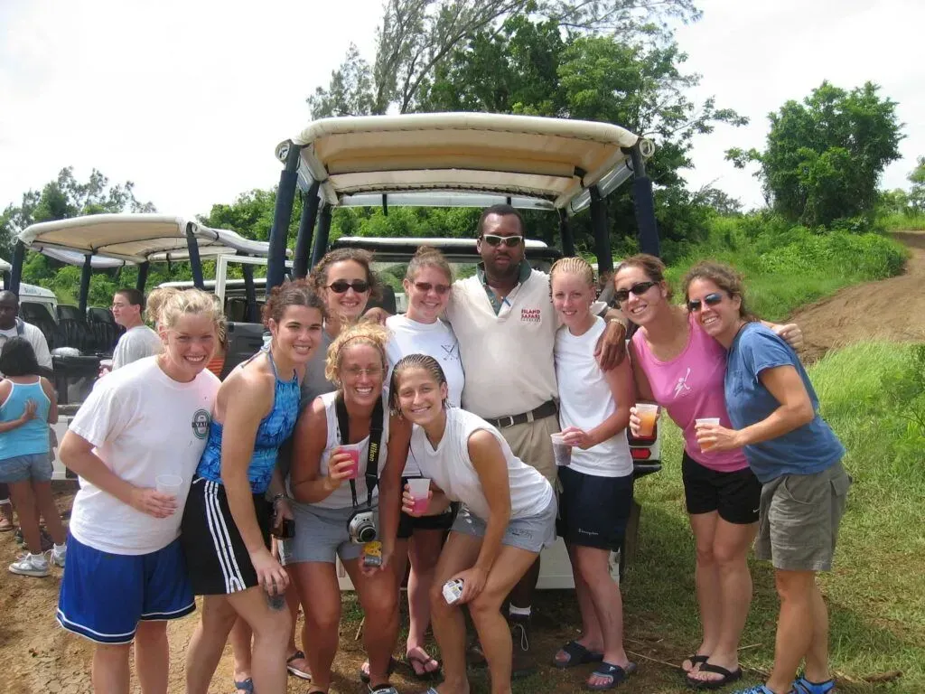 Group of smiling hikers posing on a safari cart in a lush outdoor setting