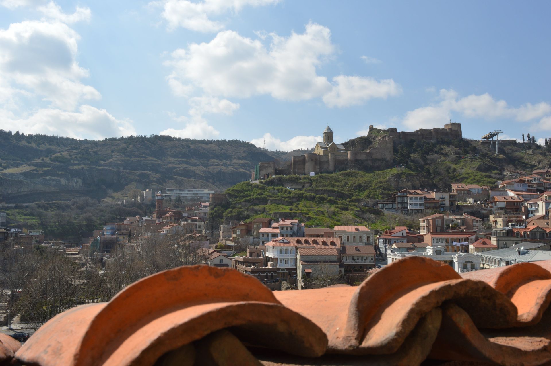 Hilltop town with terracotta rooftops beneath a blue sky and mountains in the distance