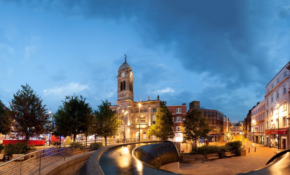 Historic building and canal at dusk, with lit streetlamps and evening sky