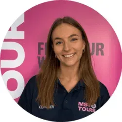 Smiling woman in navy polo in front of a pink MS Tours backdrop