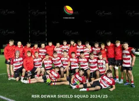 Rugby team in red and white striped jerseys posing on a field with a “R5R Dewar Shield Squad 2024/25” banner
