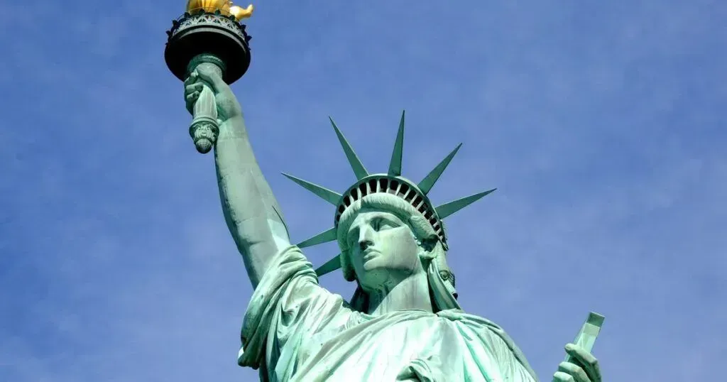 Statue of Liberty against a clear blue sky, holding a torch aloft