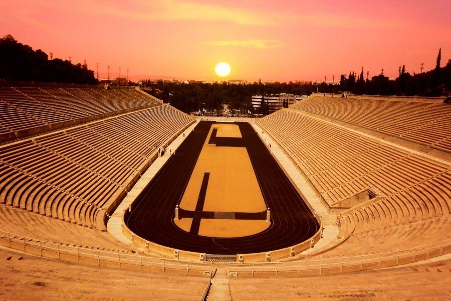 Sunset over an empty outdoor stadium with orange seating and a dark central field