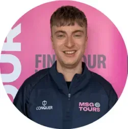 Smiling person in a navy MSG Tours jacket standing before a pink backdrop