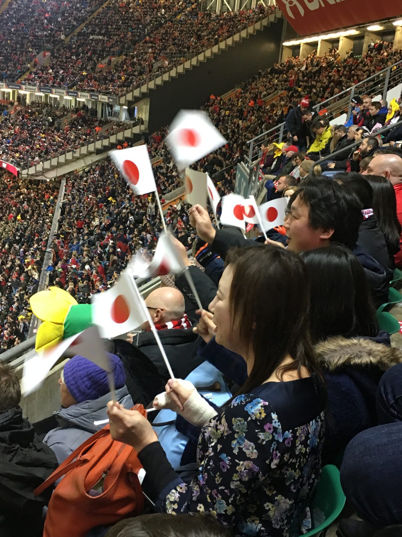 Crowd waving Japanese flags at a packed indoor stadium event